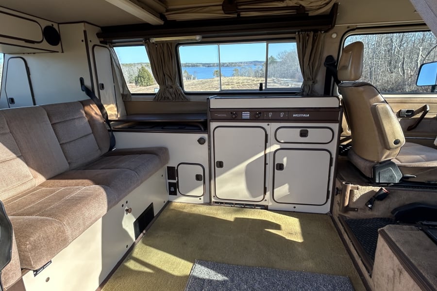 Bright Westfalia camper interior: kitchen, bench, and lake views. Ideal for your next rv rental trip.