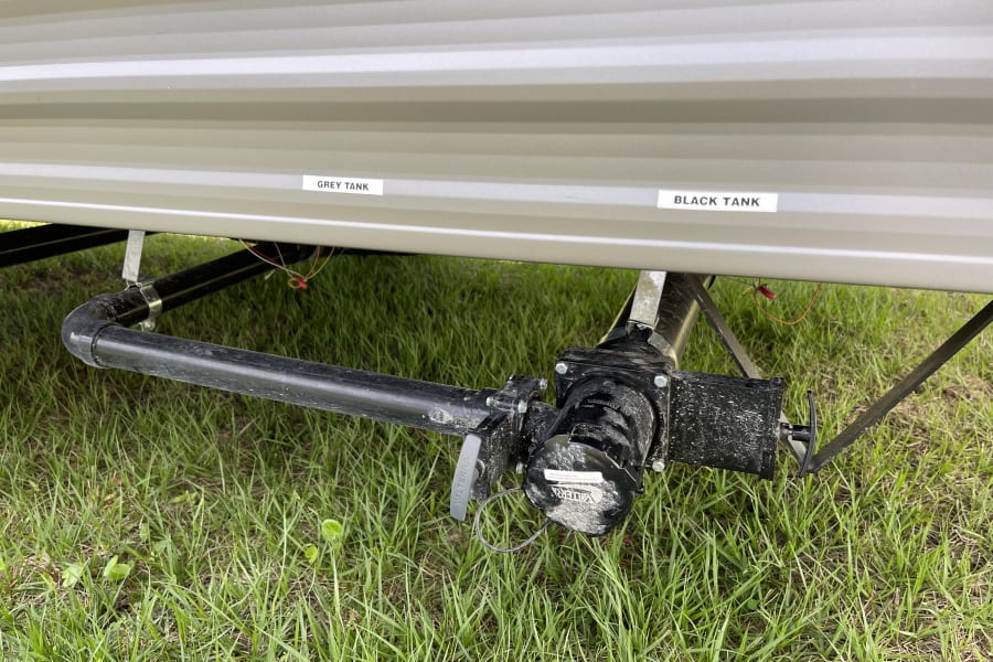 RV rental: Underside view of grey and black tank waste plumbing valves.