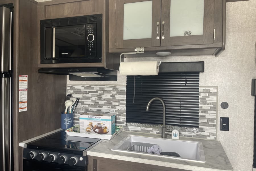 Full kitchen- farmhouse size sink, refrigerator/freezer, 3 burner gas stove, oven, and microwave. 