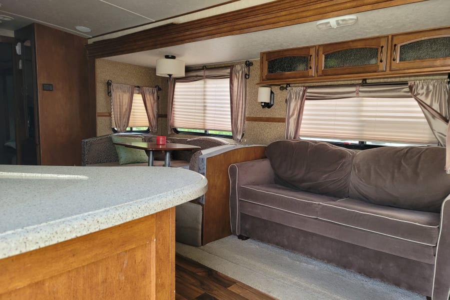 Comfortable RV rental interior featuring a living area with a sofa, dinette seating, and a kitchen counter.