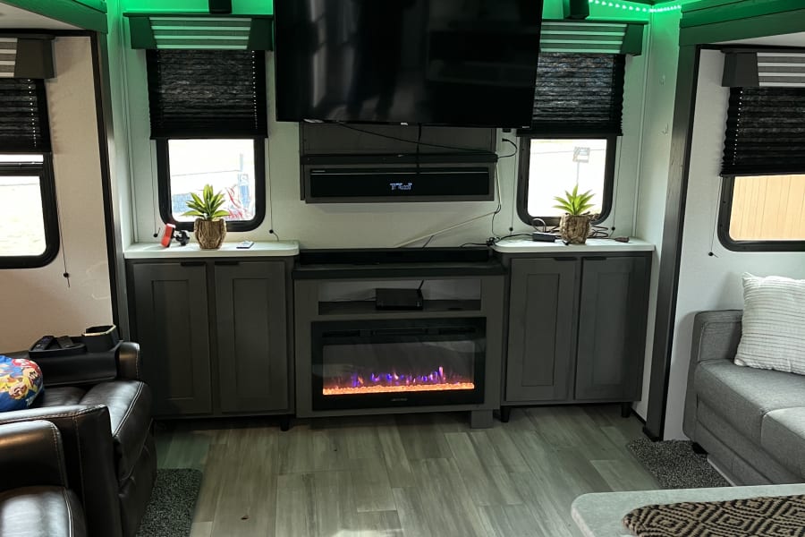 Step inside this RV rental's well-appointed living area, complete with a TV, electric fireplace, and stylish green LEDs.