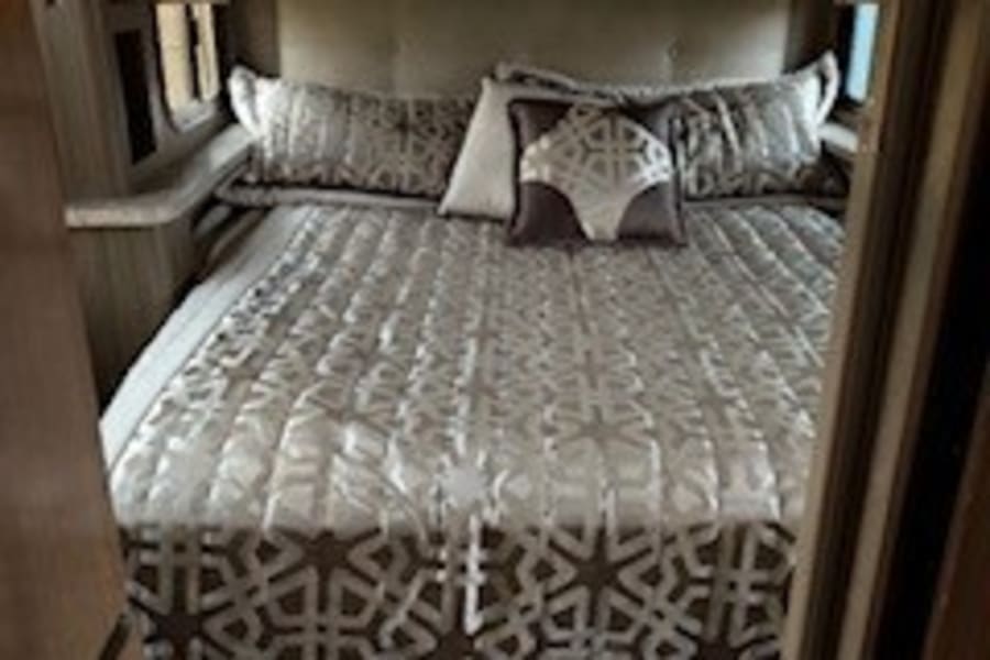Experience comfortable travel! This cozy RV rental bedroom offers a queen bed, decorative bedding, and ample storage for trips.