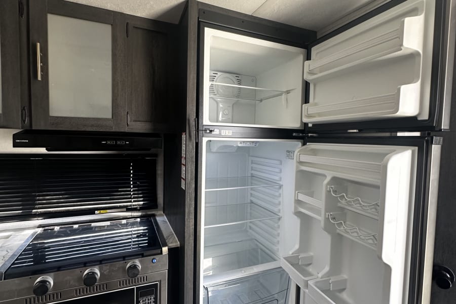 Essential amenities in this RV rental kitchen: large fridge, stove/oven, microwave, and ample storage.