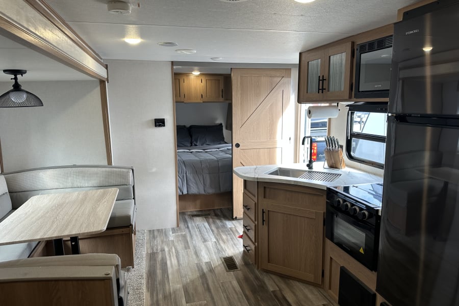 Spacious RV rental interior featuring a full kitchen, dinette, and bedroom, offering comfort for your travels.