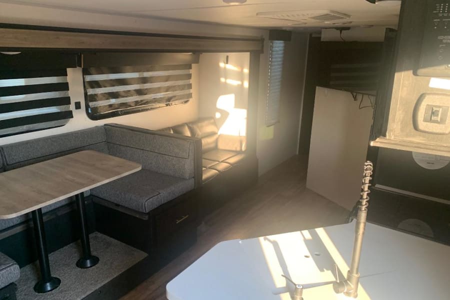 Spacious RV rental interior featuring a comfy dinette, kitchen, and living area bathed in sunlight.