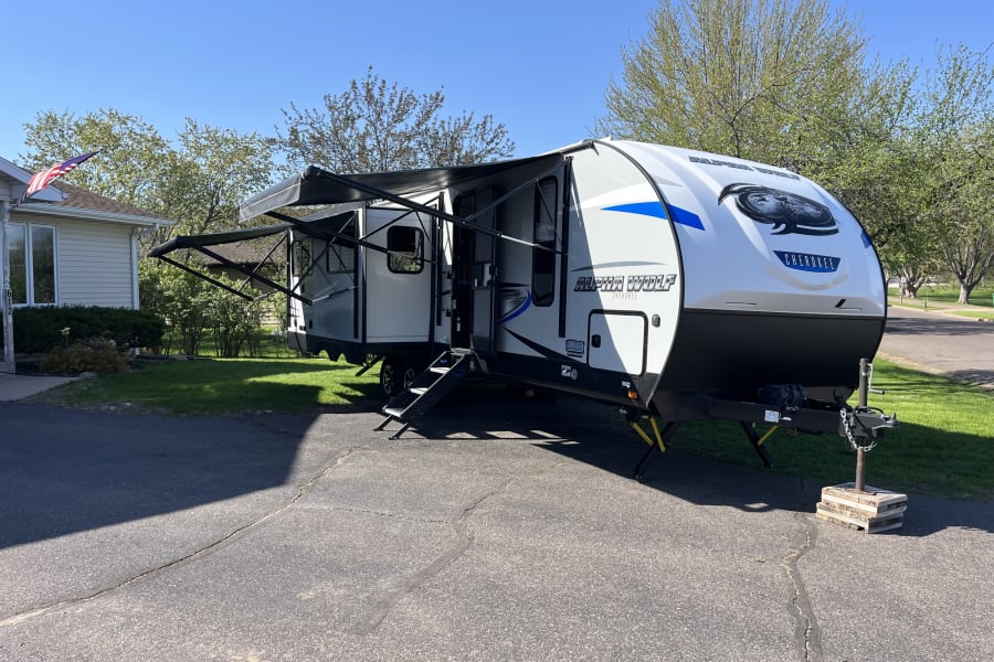 White Alpha Wolf travel trailer with awnings extended, ready for your next RV rental adventure.
