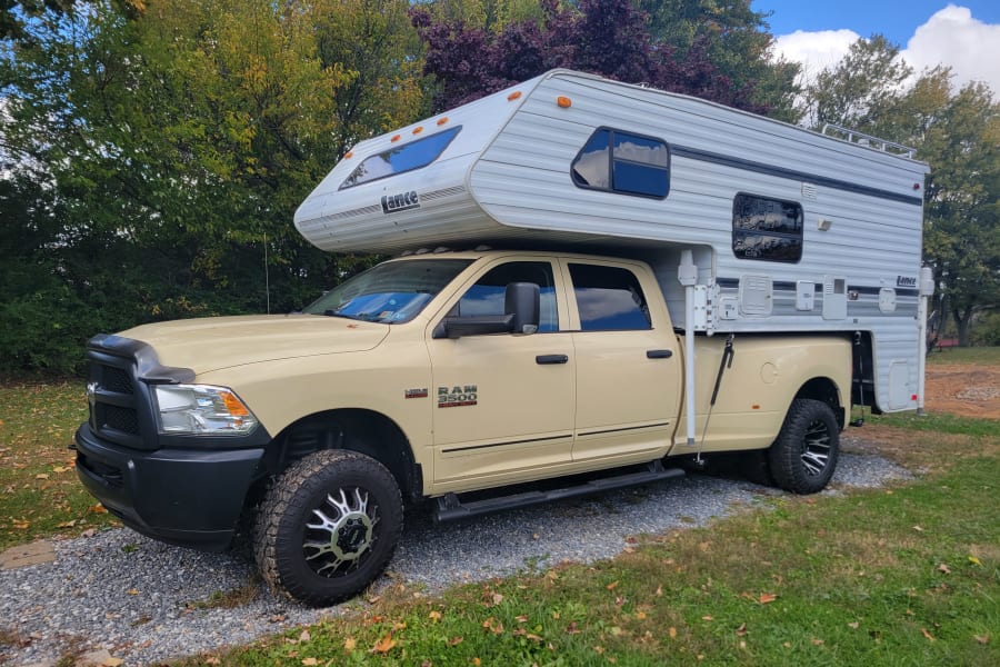 A Ram 3500 dually truck with a Lance truck camper mounted in the bed, available for rv rental adventures.