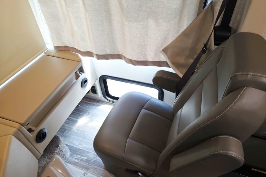 RV rental interior showcasing a comfortable driver's seat, side console with vents, and a window. Ready for the road.