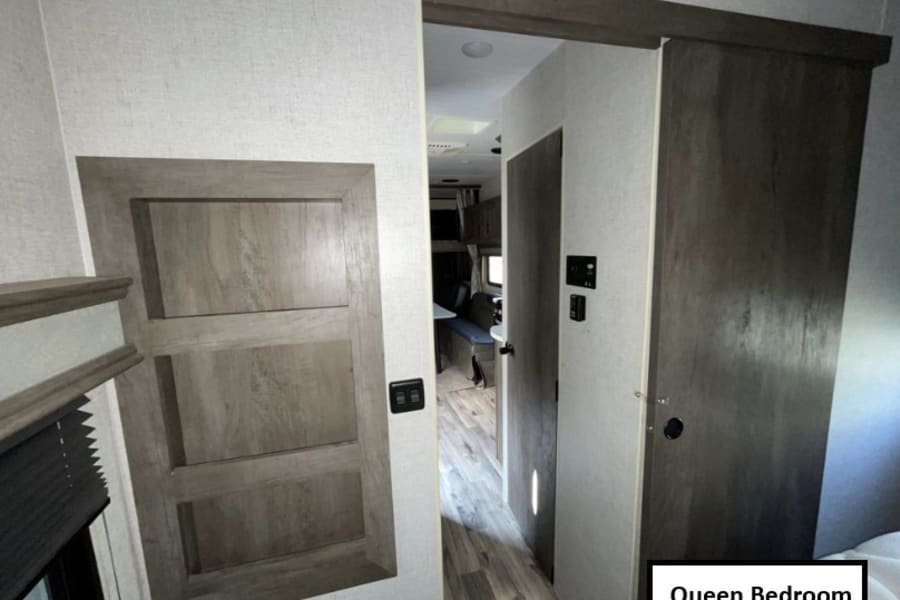 RV rental interior: View from the queen bedroom showing built-in storage, and a sliding door leading to the living area.