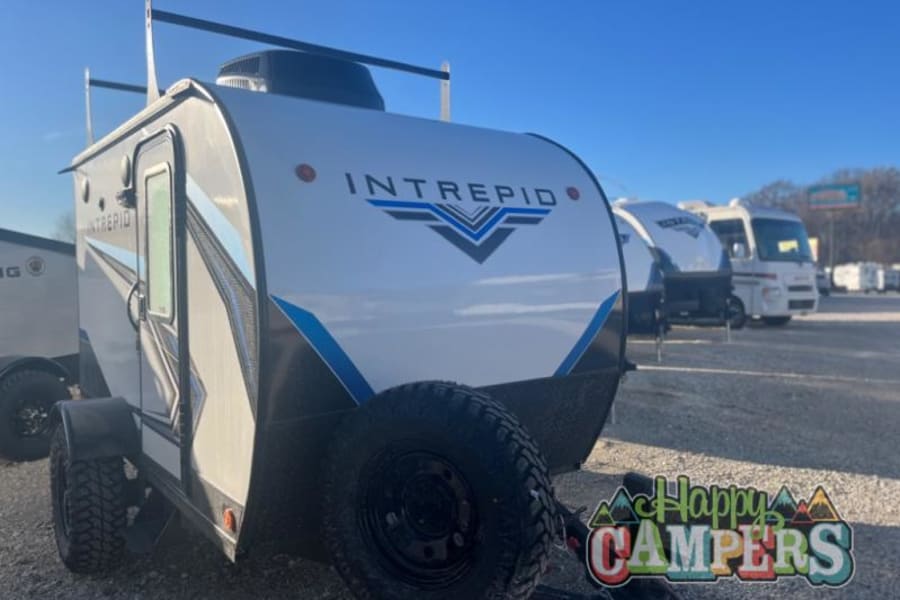 Ready for your next trip? This white Intrepid travel trailer RV rental, featuring off-road tires and roof rack, is perfect for camping.