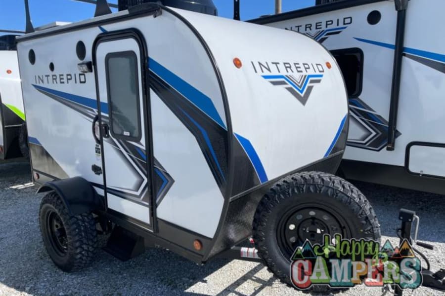 Front view of a rugged Intrepid travel trailer RV rental, white with blue accents, ideal for off-grid adventures.