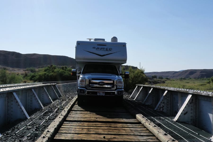 RV rental truck camper parked on an old railway bridge in a scenic valley.