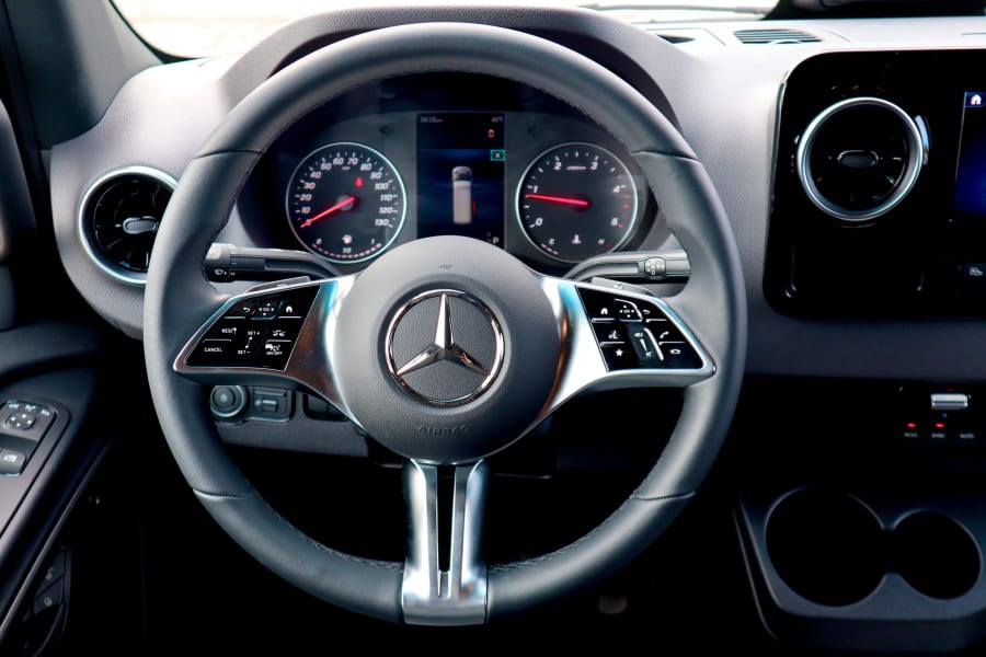 Mercedes-Benz RV rental driver's cabin: modern steering wheel, digital instrument cluster, and dashboard controls are clearly visible.