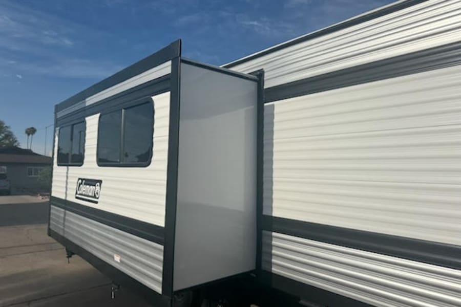 White Coleman travel trailer RV rental with a side slide-out extended for extra space.