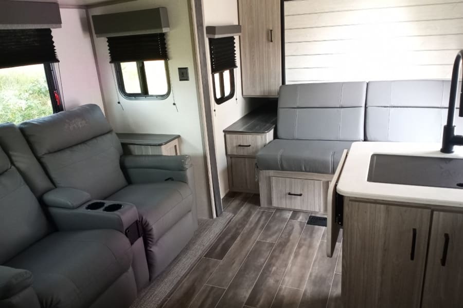 Comfortable RV rental interior featuring recliners, dinette, & kitchen. Ideal for your next road trip adventure.