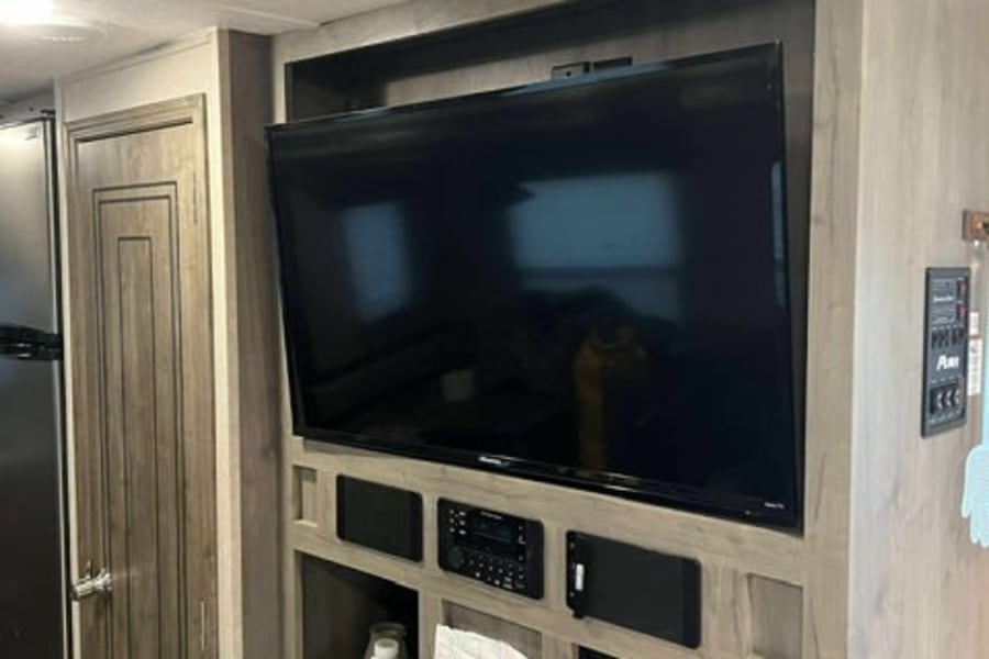 RV rental interior: A modern living space with an entertainment center, TV, and stereo system, offering comfort for travelers.