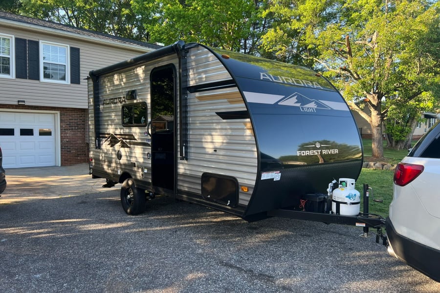 Forest River Aurora Light RV rental in driveway, ready for adventure with SUV.