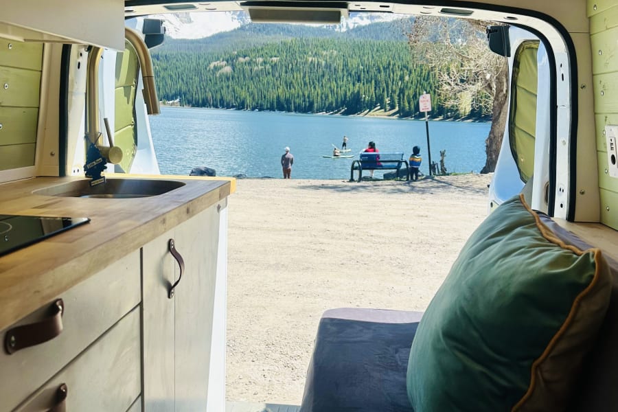 Enjoying a stunning lake view from an RV rental, complete with a cozy interior, kitchen, and nature's beauty.