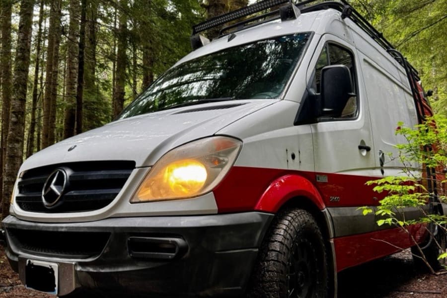 Mercedes Sprinter camper van, built for off-road adventure, perfect for rv rental, parked on a forest trail.