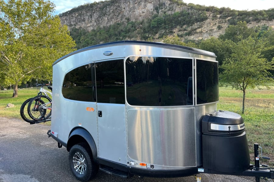 Scenic rv rental setup: A silver travel trailer with bikes parked before a majestic mountain, perfect for outdoor adventures.