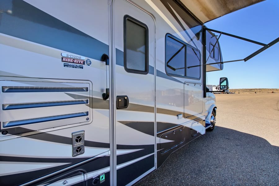 A modern RV, model 3170DS, shows its side with an extended awning, ideal for your next rv rental trip.