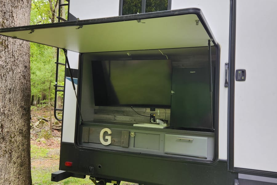 This RV rental offers outdoor entertainment with a TV & mini-fridge, perfect for camping fun.
