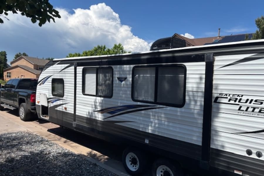 Side view of a white Salem Cruise Lite travel trailer hitched to a truck, ready for an rv rental journey.