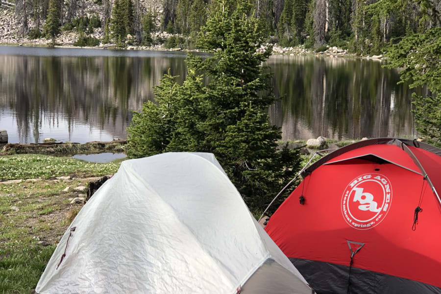 Two tents by a stunning mountain lake. Experience nature's raw beauty by primitive camping or with an RV rental for broader exploration.