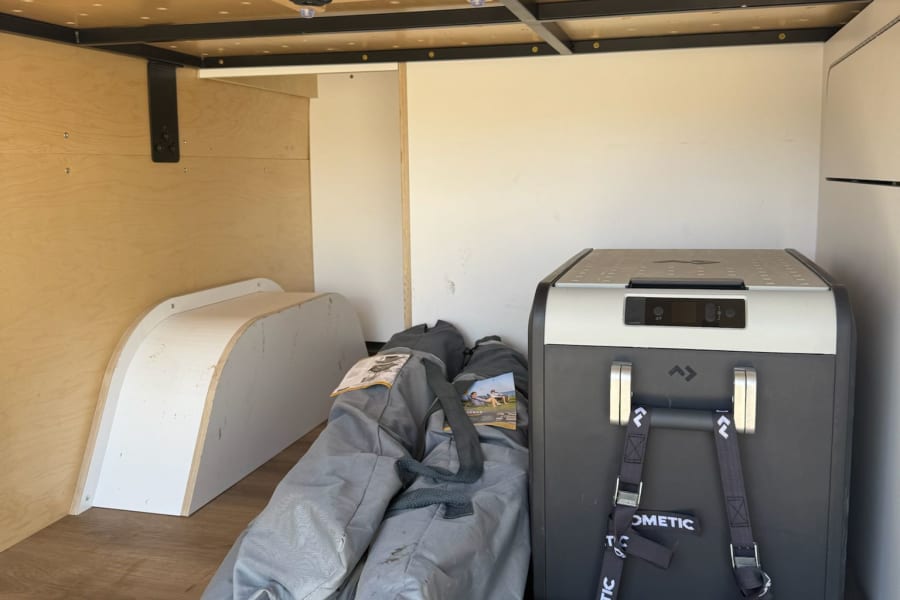 Inside an **RV rental**: Dometic cooler secured on a pull-out tray, ready for adventure with organized gear and storage.