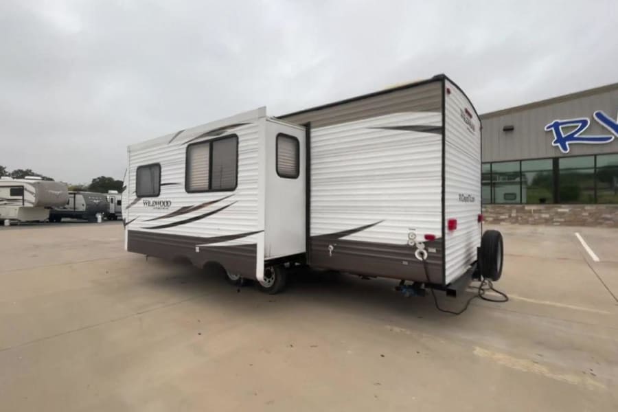 A Wildwood travel trailer with slide-out extended, parked on a lot at an RV rental dealership. Ready for adventure.