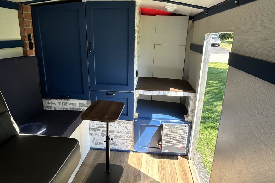 Custom camper interior for your RV rental, with blue cabinets, seating, adjustable table, and a roof fan for cozy travels.
