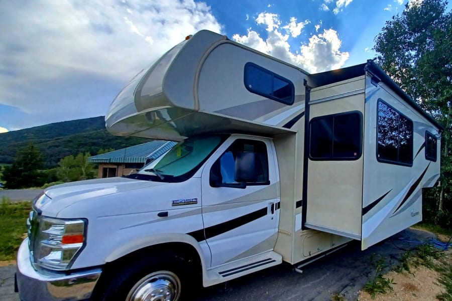 This Class C RV rental, with its slide-out extended, is parked in a scenic setting, ready for your next camping adventure.