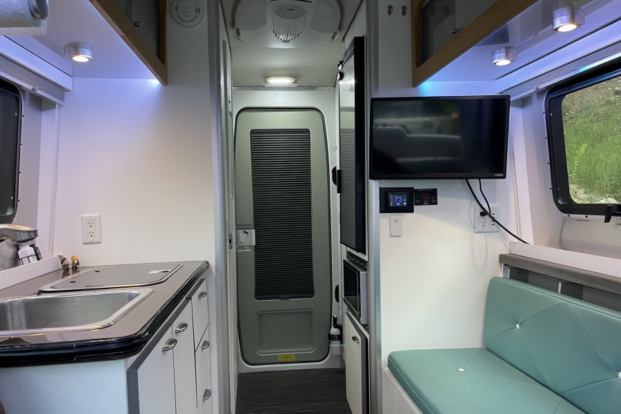 Compact RV rental interior featuring a modern kitchen, cozy seating, and essential amenities.