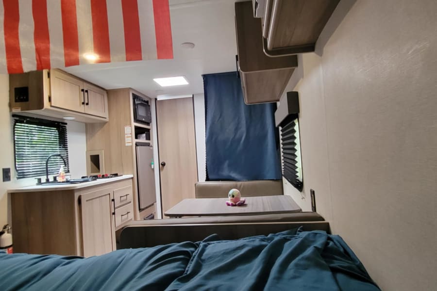 RV rental: Bright interior with a full kitchen, dinette, and cozy living space. See the striped flag and octopus toy.
