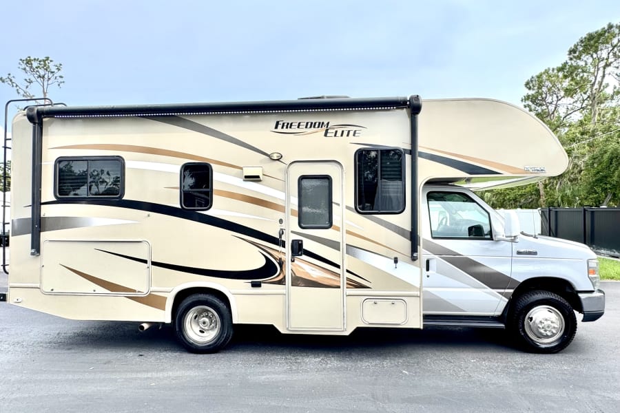 Side view of a two-tone beige and brown Freedom Elite Class C motorhome, available as an rv rental.