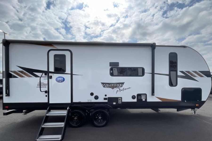 White Wildwood Platinum RV rental travel trailer, perfect for camping adventures, with steps, awning & modern design.