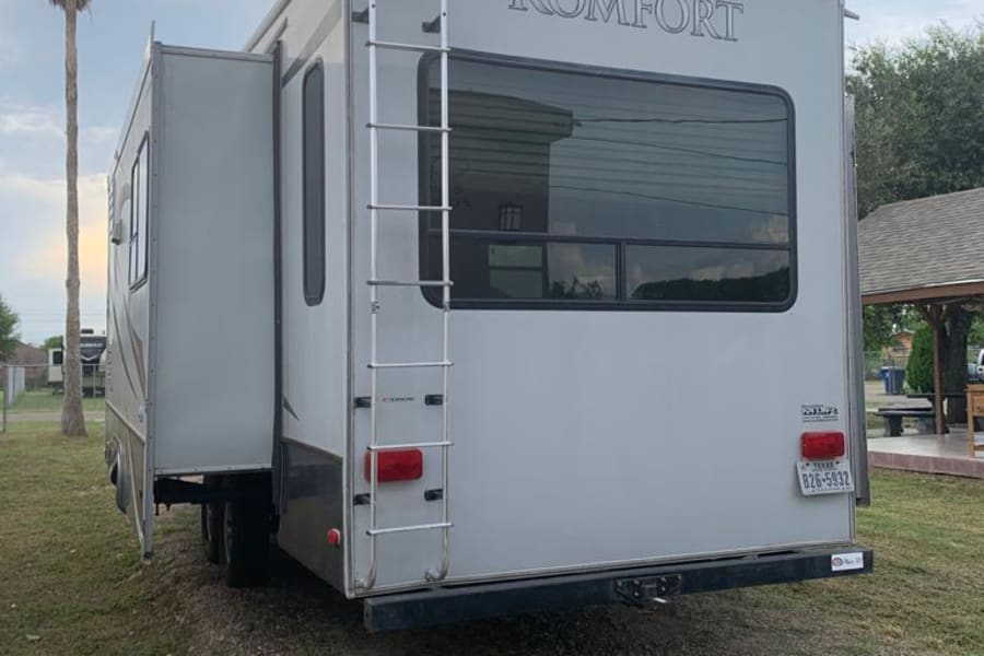 Rear view of a spacious Komfort RV rental with an extended slide-out and ladder, ideal for a Texas road trip.