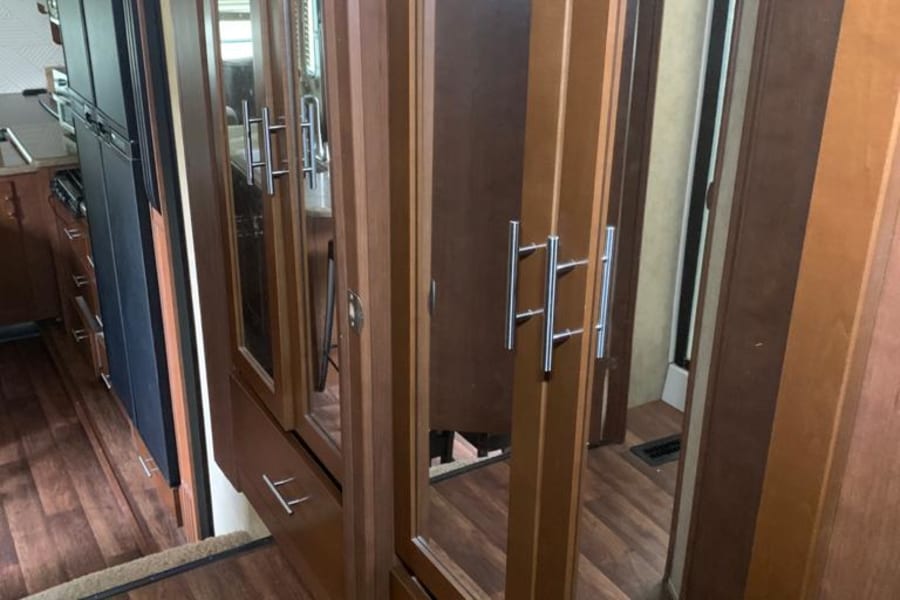 RV rental interior: wood floors lead to spacious mirrored cabinets and a glimpse of the kitchen area.
