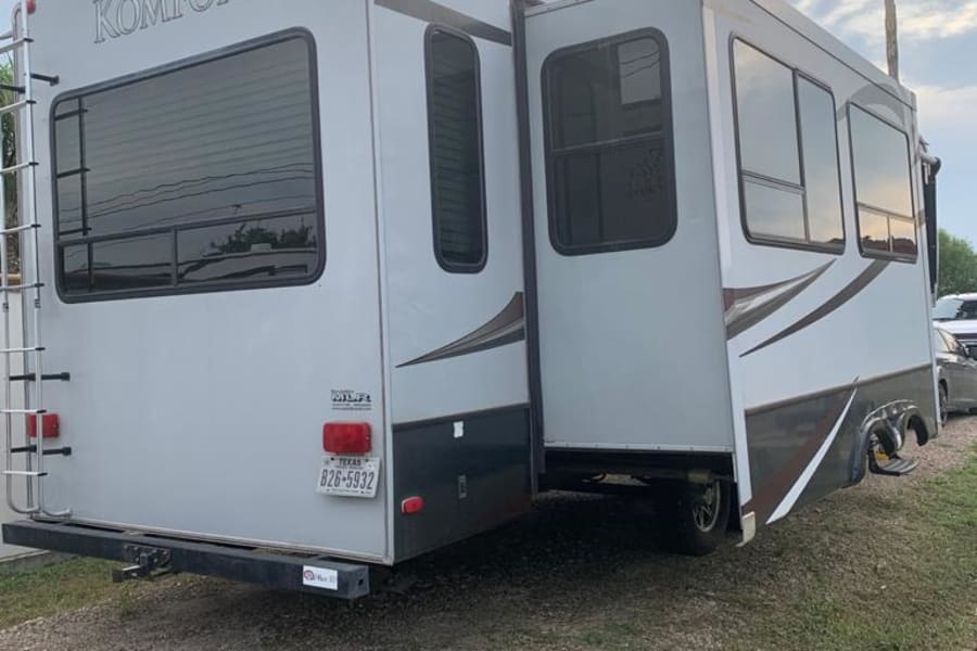 Explore this spacious Komfort RV rental, a travel trailer with extended slide-out and Texas plate, parked outdoors.