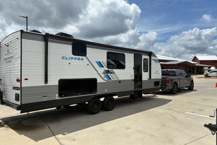 A white & gray Coachmen Clipper travel trailer with a dark gray pickup truck. An ideal setup for an rv rental.