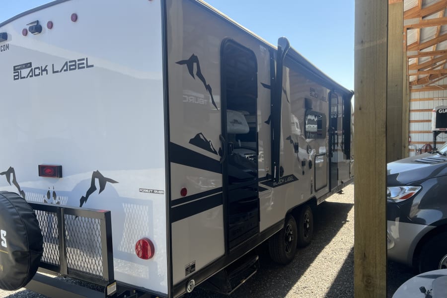 This Forest River Black Label travel trailer, possibly an rv rental, is ready for adventures with its rear rack.