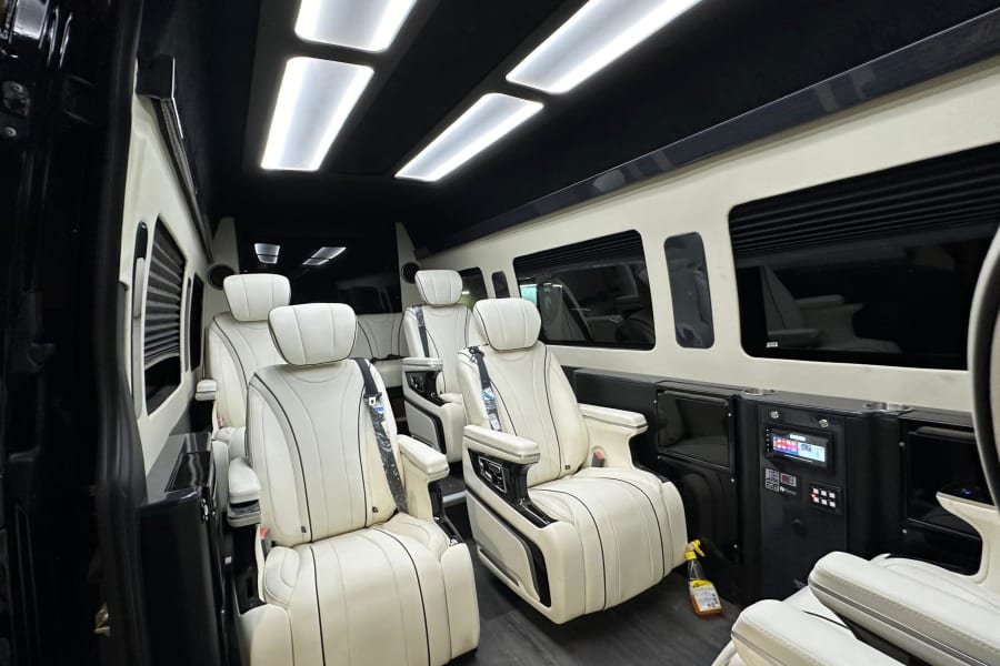 Luxury RV rental interior: spacious cabin with white captain seats, bright LED lighting, and side control panels.