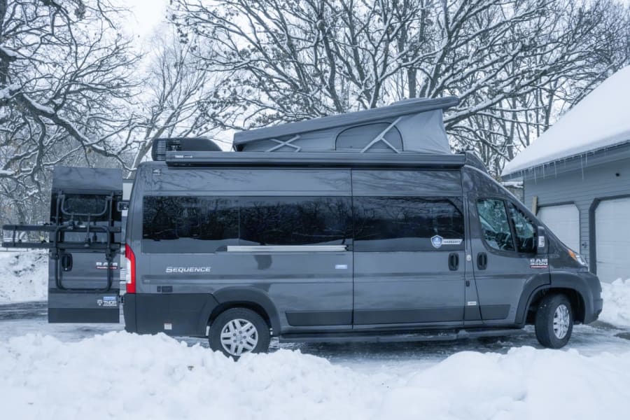 **RV rental**: Grey Thor Sequence camper van with deployed pop-top, bike rack, and awning, parked in snow.