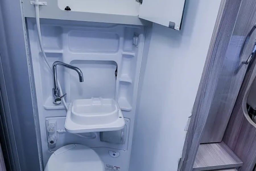 This RV rental features a compact wet bath with a shower, fold-down sink, and toilet, maximizing space for travelers.