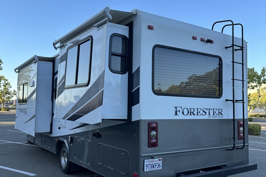 RV rental: A white and grey Forester Class C motorhome with slide-out extended, parked on asphalt.
