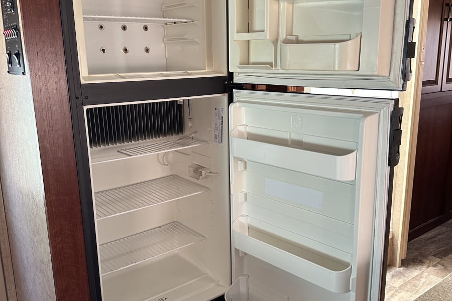 RV rental: Bright, clean, and empty two-door refrigerator, ready to be stocked for your adventure kitchen.
