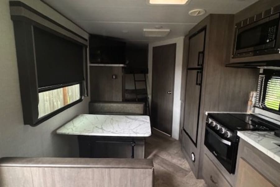 This spacious RV rental interior features a dinette, full kitchen, and bunk beds, perfect for your