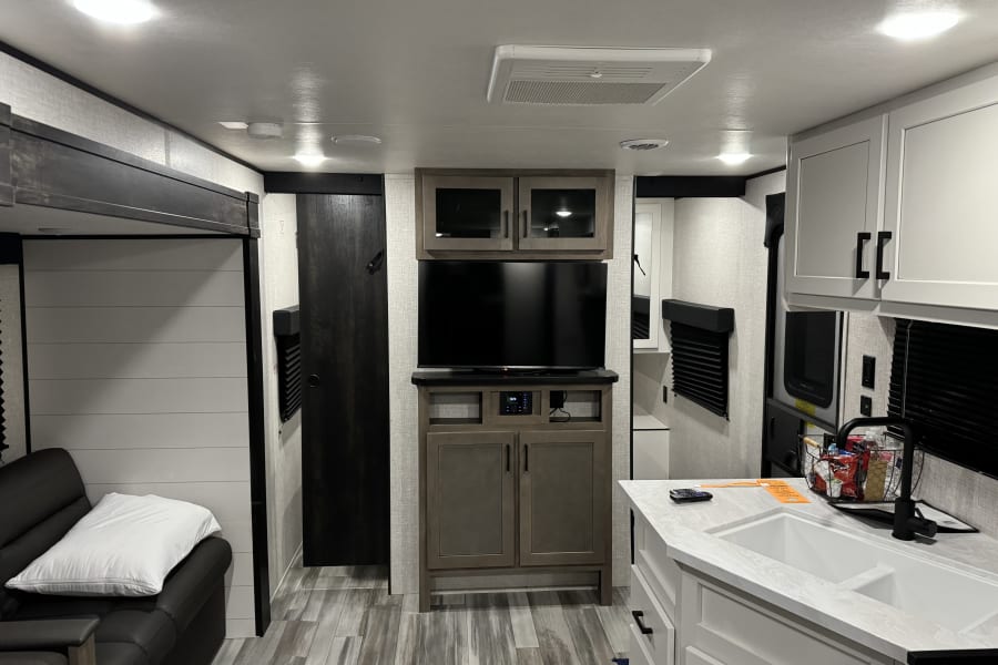 Spacious RV rental interior featuring a modern kitchen, living area with couch, and entertainment setup.