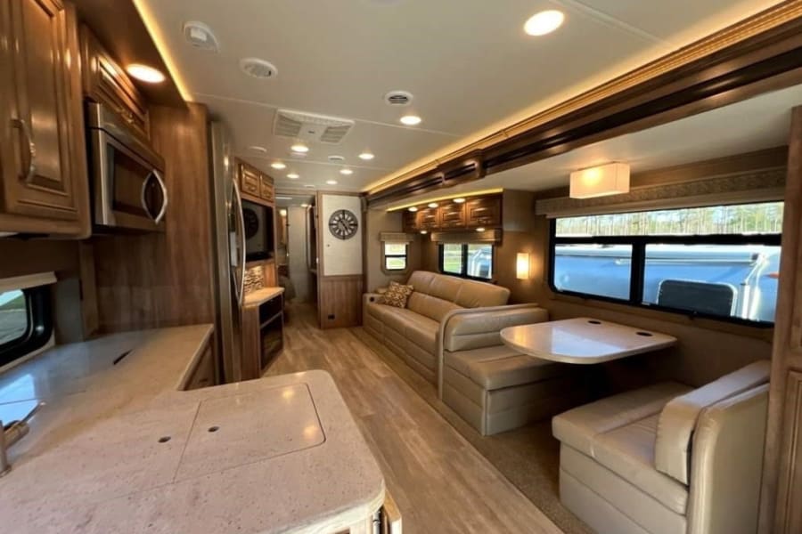 Spacious rv rental interior showcasing a bright kitchen, large lounge sofa, and cozy dinette with modern finishes.