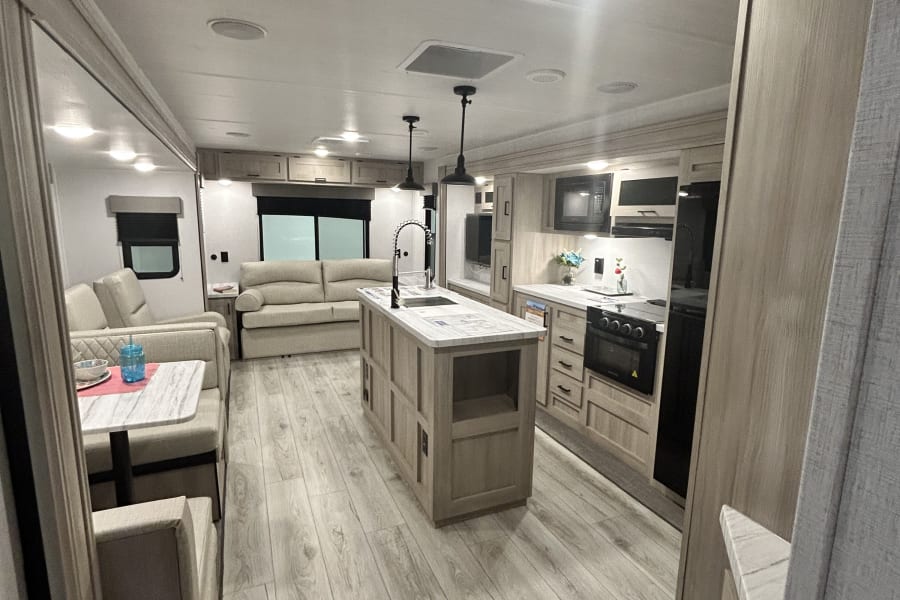 Spacious RV rental interior with modern kitchen, island, and living area. Perfect for a cozy getaway.